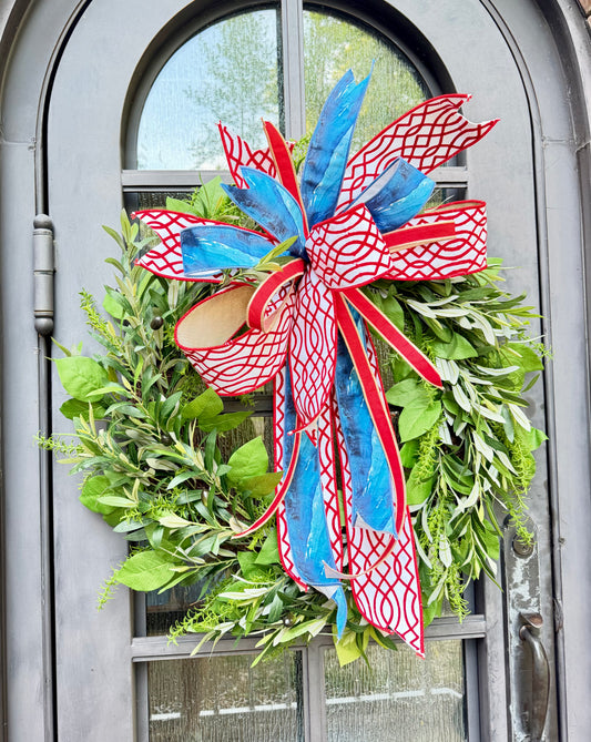 30 inch faux olive, Rosemary, and lemon leaf wreath. Paired with a JME red white and blue bow. Some fluffing may be required upon arrival. 