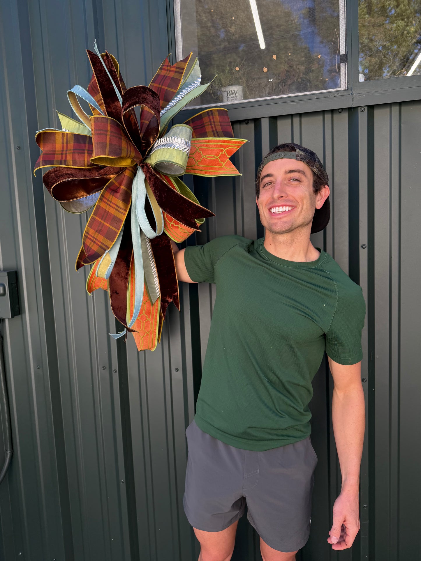 JME HAND TIED FALL BOW with a fall plaid parked with orange velvet and green embroidery ribbon and coordinating ribbons. About 22 inches wide by 30 long. Some fluffing may be required upon receiving.