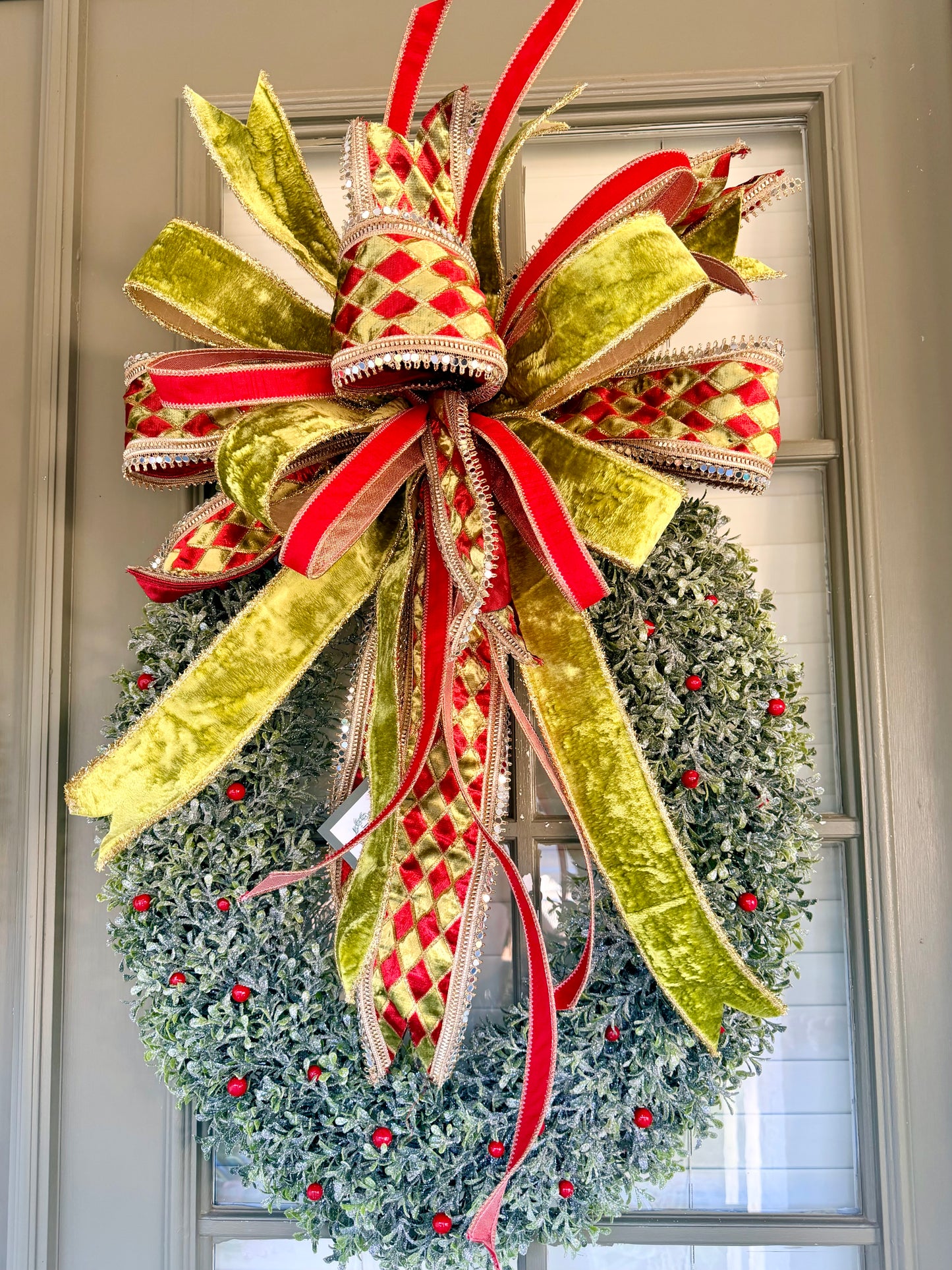 The Oval Wreath. Glittered icy oval wreath paired with A JME hand tied bow. About 22 inches wide and 32 inches long. *Some fluffing may be required upon receiving.