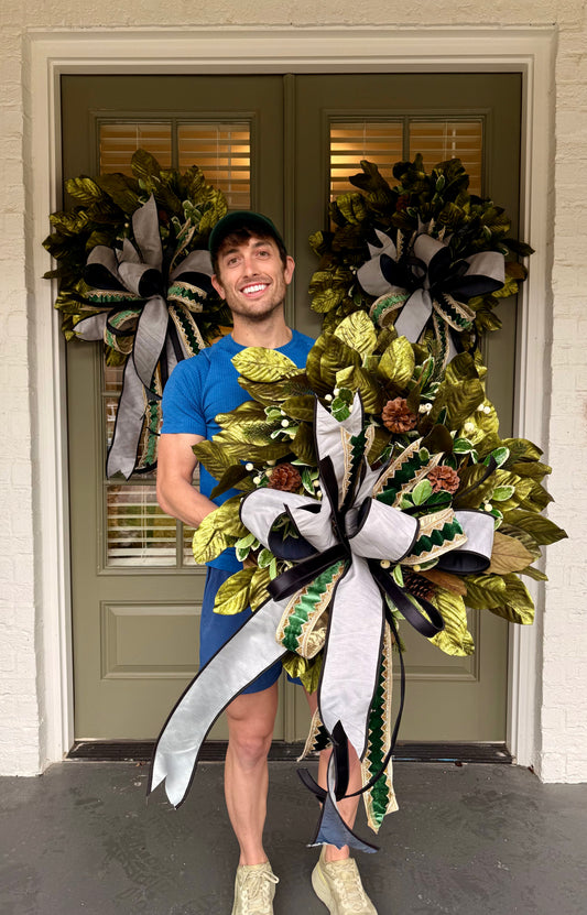 Handmade wreath with metallic green magnolias and a sophisticated JME handtied bow. About 24inches wide.