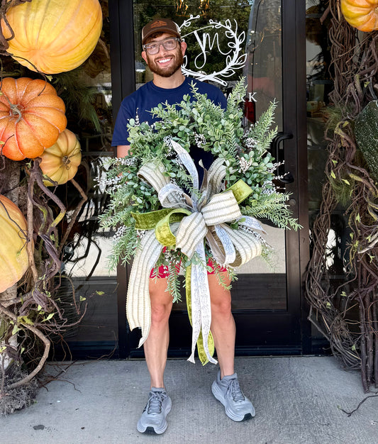 Green mixed foliage wreath with small white berries and a hand tied JME BOW. About 24in wide.