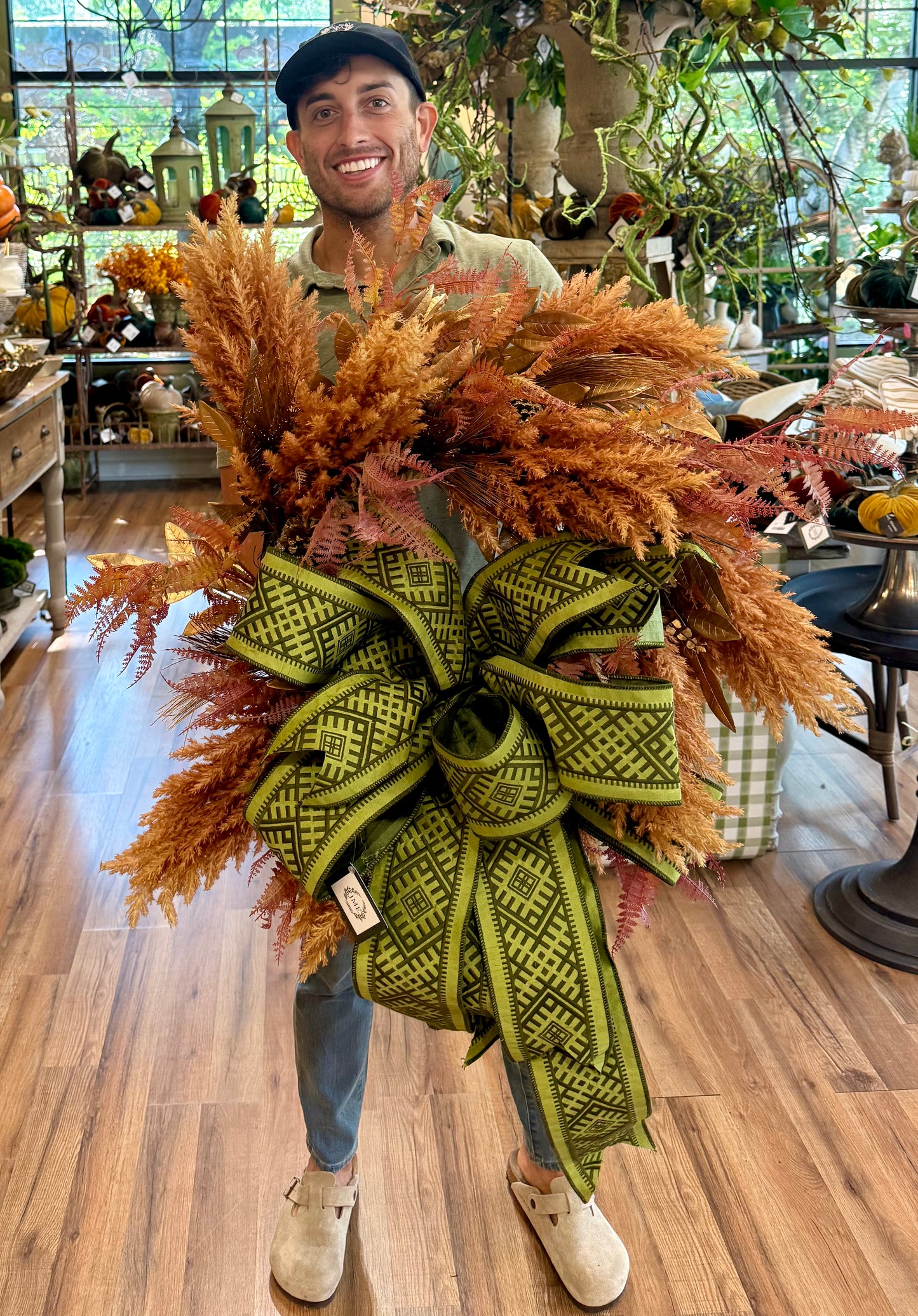 JME MADE faux fall pampas grass wreath with an JME embroidered bow. About 25 inches wide.
