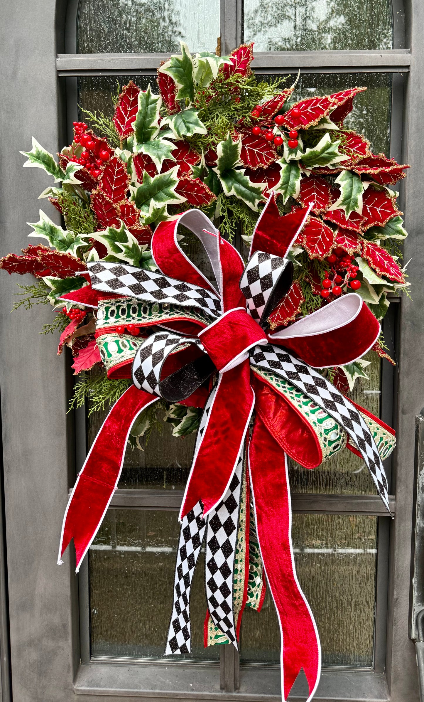 Glitzy Christmas wreath. Hand made by JME , adorned with velvet red holly leaves and paired with a JME bow. Mirrored ribbon and red velvet. What more could you asked for? About 24 inches wide