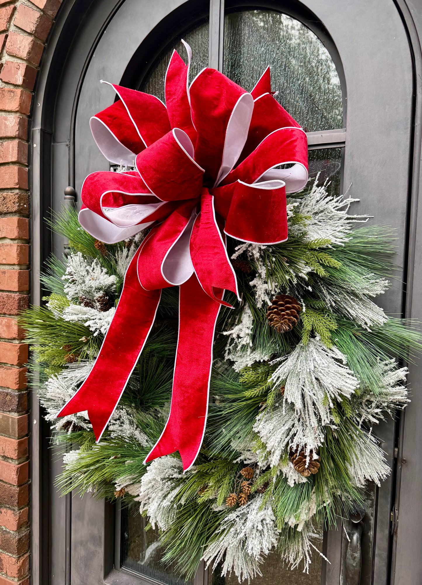 Big Flocked mixed foliage wreath with a JME hand tied bow in it. Red velvet backed with white taffeta. 36inches wide
