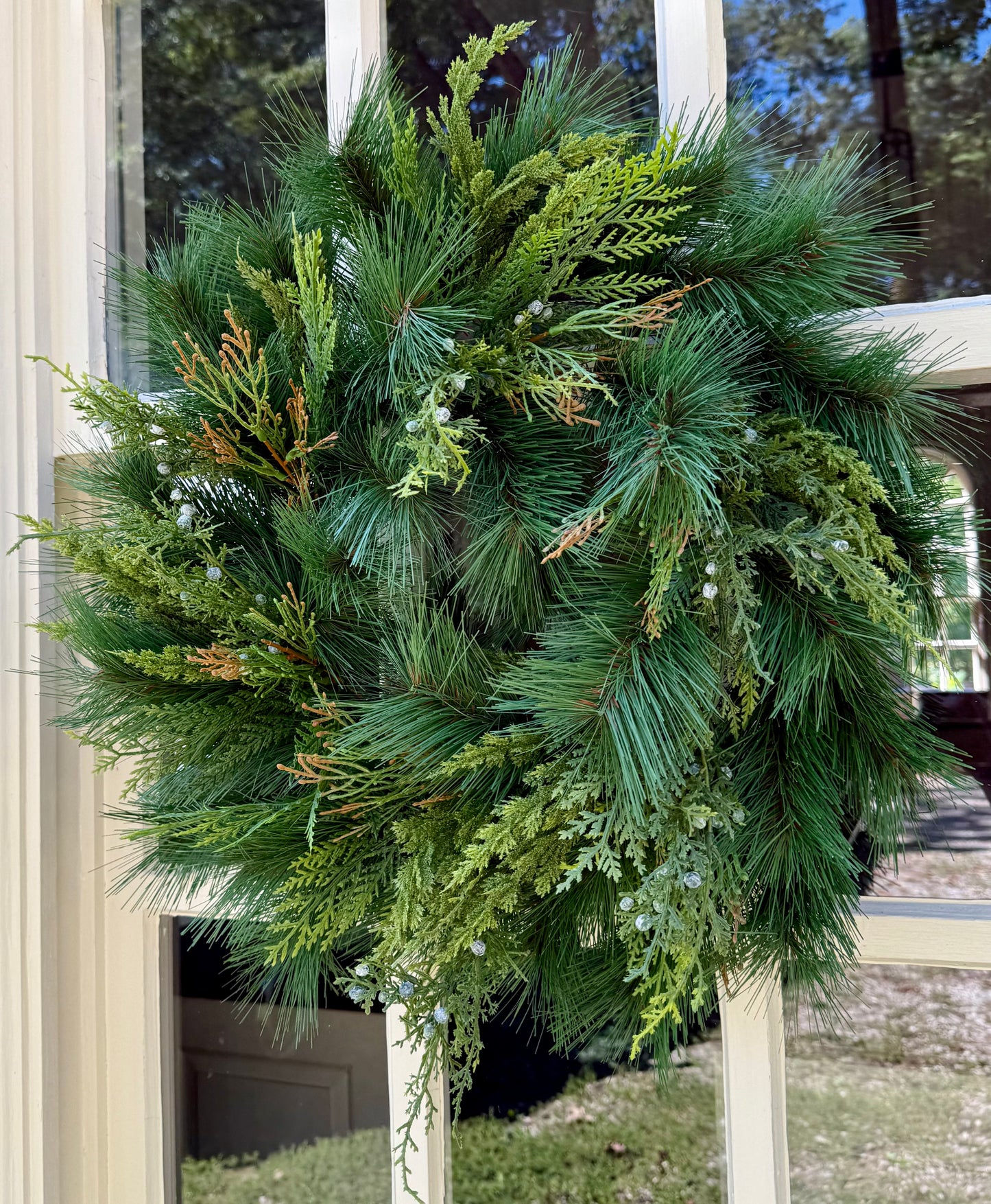 Faux mixed foliage wreath with Juniper and Cedar. 24 inches. Perfect for windows, mirrors, doors and more! Beautiful alone or with a simple bow.