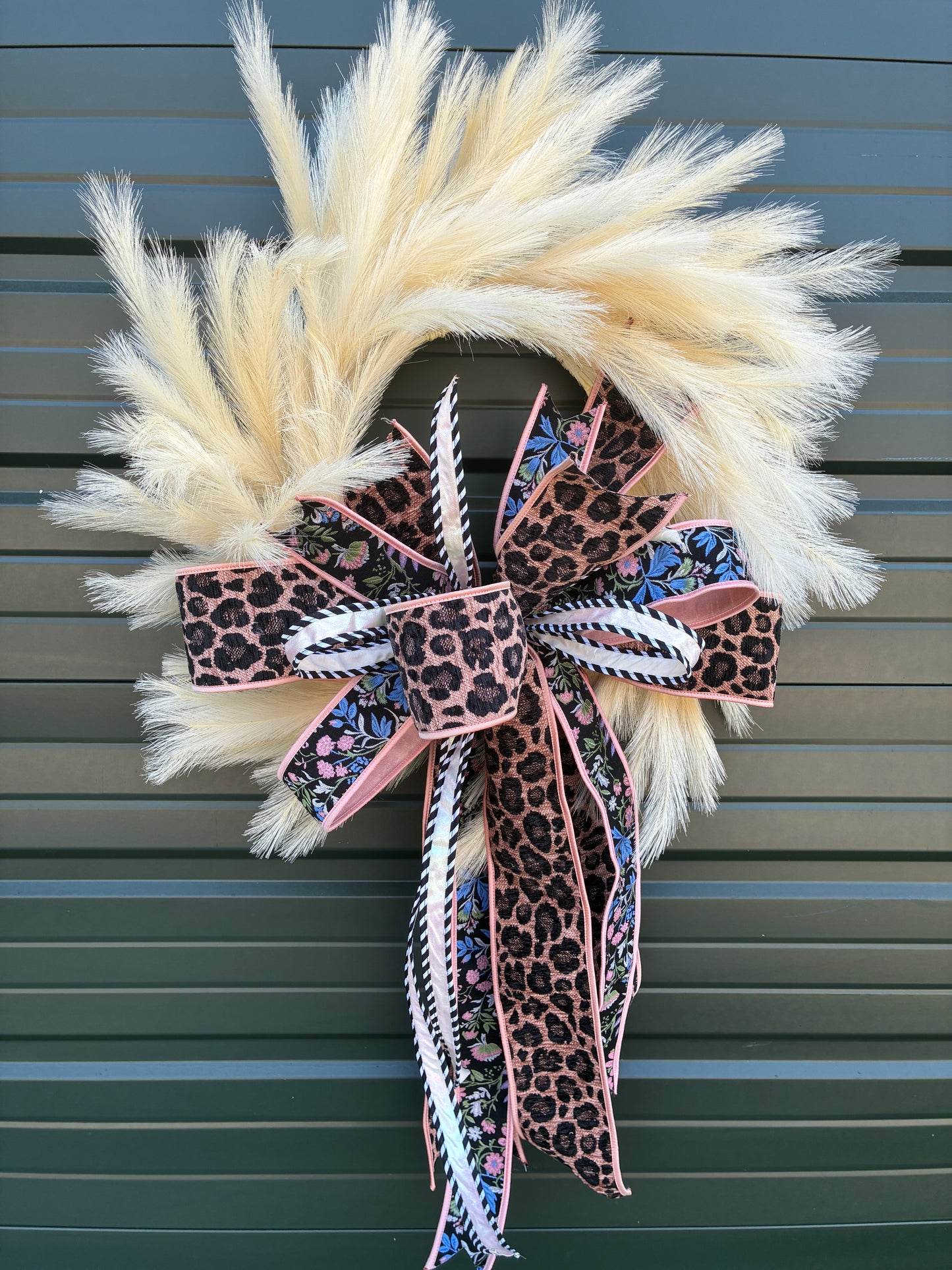 Faux Cream Plume Wreath paired with a JME hand tied bow featuring a pink and black Leopard Chenille and floral ribbon combo. Approximately 26 inches in diameter. Some fluffing may be required upon arrival.