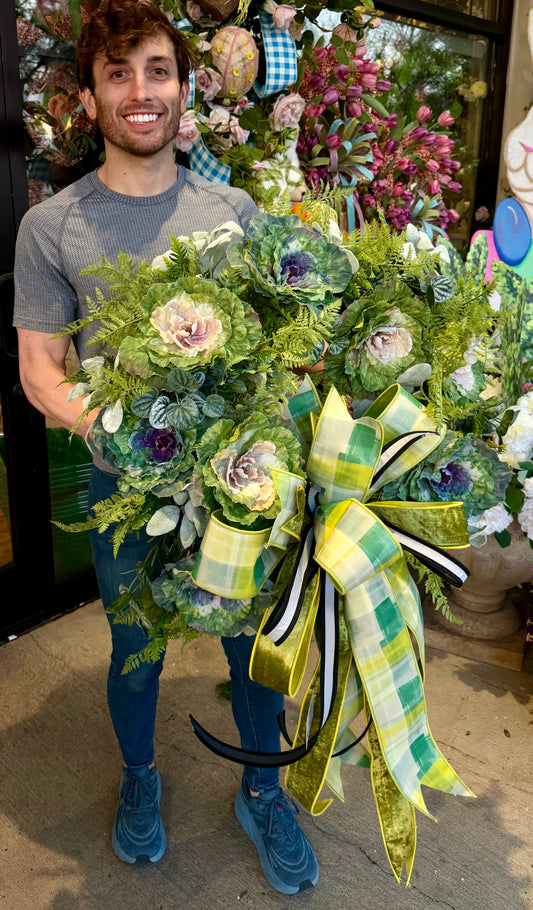 JME handmade wreath. Made of mixed cabbage/lettuce and foliage. About 30 inches in diameter. Paired with a JME hand tied yellow and green bow.