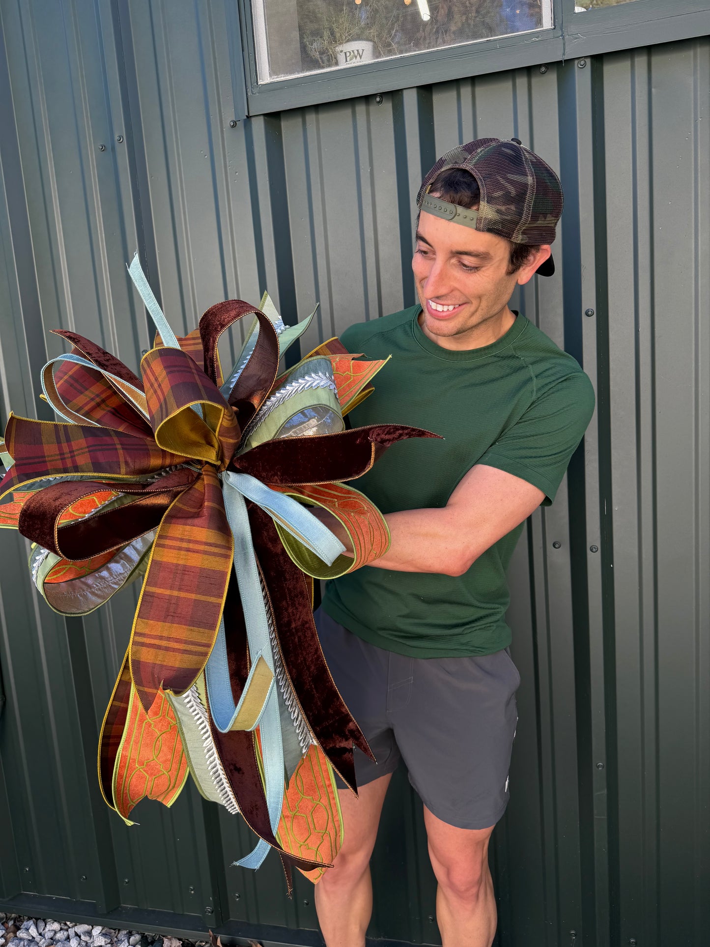 JME HAND TIED FALL BOW with a fall plaid parked with orange velvet and green embroidery ribbon and coordinating ribbons. About 22 inches wide by 30 long. Some fluffing may be required upon receiving.