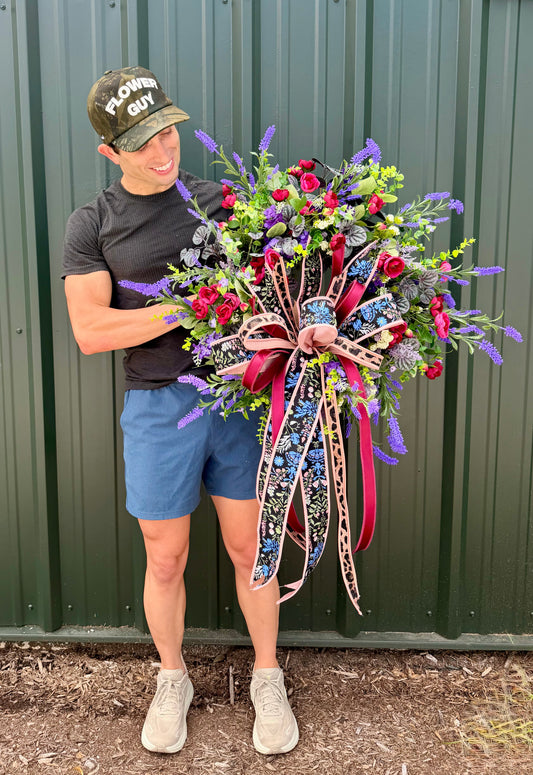 JME HANDMADE WREATH. Lush deep colors of purples and burgundies. Paired with a JME hand tied bow. About 26 inches wide.