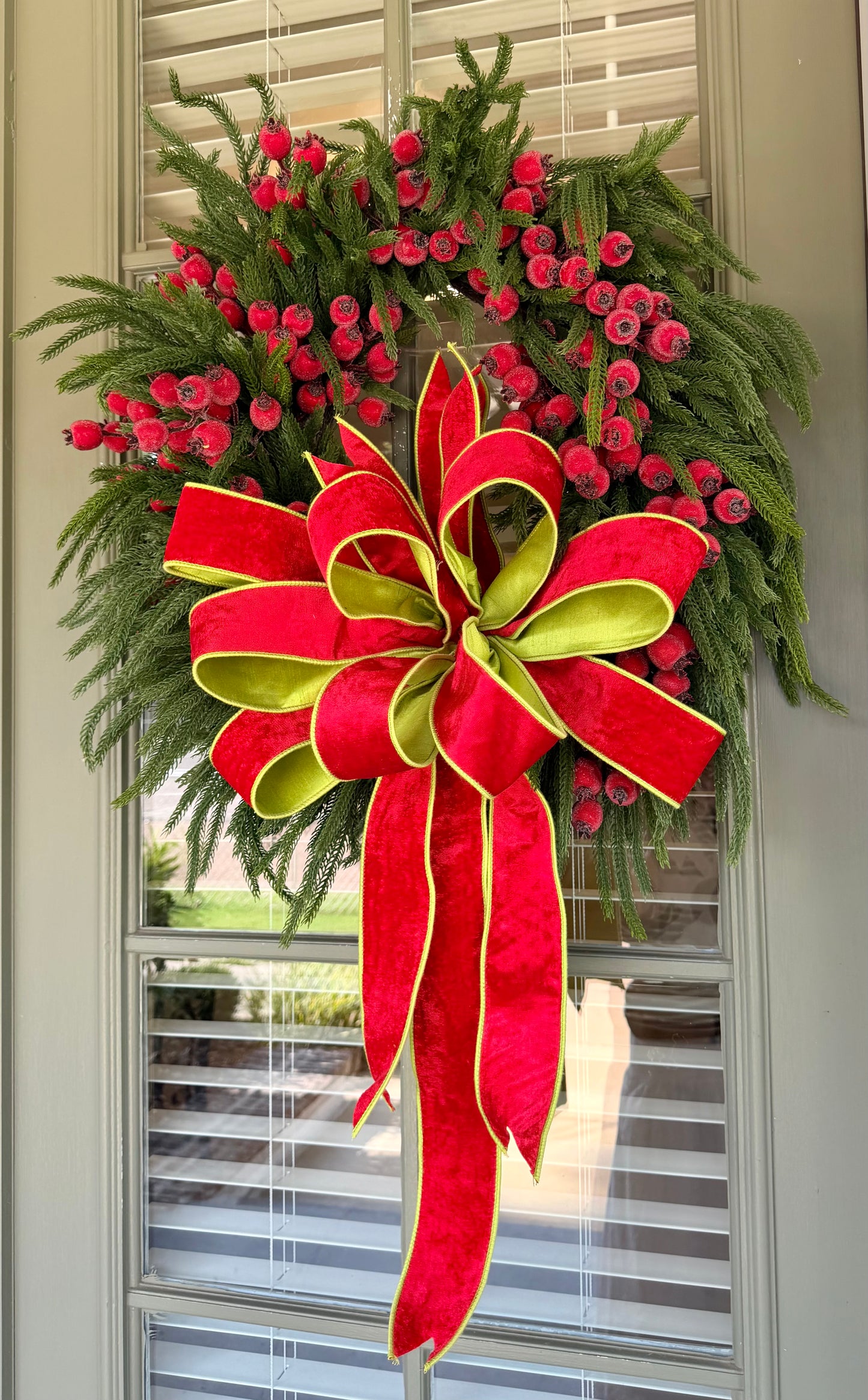 JME faux pine wreath with red berries and a  JME red velvet bow with chartreuse accents. About 26 inches in diameter. Some fluffing may be required upon receiving. ￼