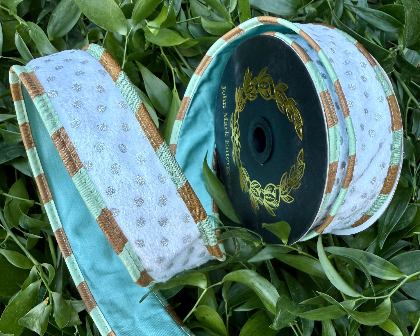 JME heavy wired ribbon. White velvet with silver polkadots piped with a brown and teal checked. Backed with aqua ribbon. 1.5” x 10 yard.