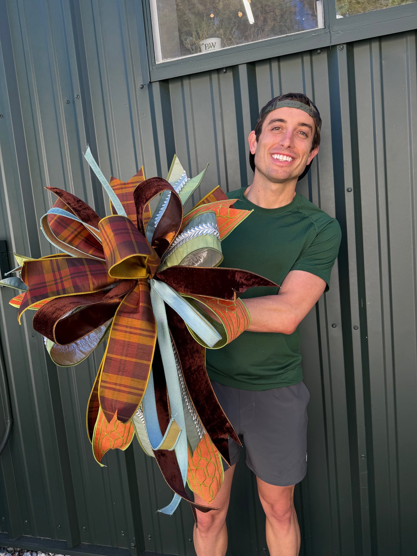 JME HAND TIED FALL BOW with a fall plaid parked with orange velvet and green embroidery ribbon and coordinating ribbons. About 22 inches wide by 30 long. Some fluffing may be required upon receiving.