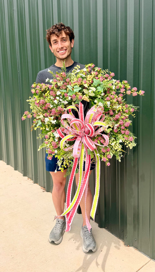 Handmade JME summer meadow wreath. Paired with a JME hand tied bow of 1 in ribbons in pinks, green, and coral. About 24inches in diameter