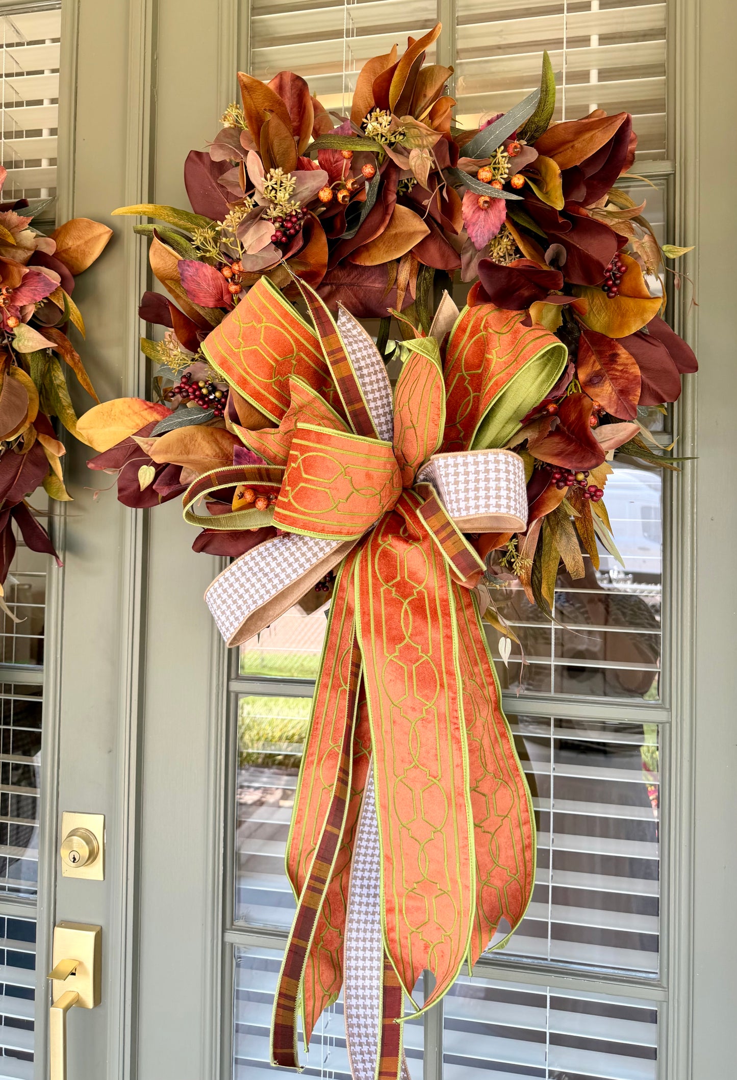 JME fall faux MAGNOLIA WREATH paired with other fall botanicals. About 26inches in diameter. Paired with a JME hand tied bow of orange and browns. Some fluffing may be required upon receiving.