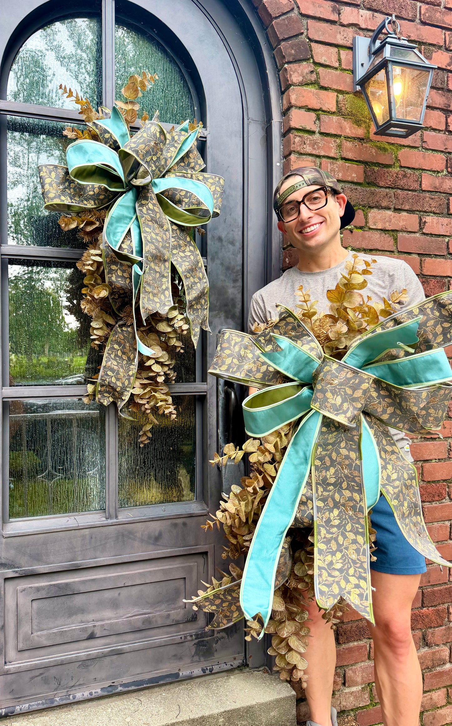 Handmade JME fall door swag made with faux brown eucalyptus. Paired with a beautiful floral grey and teal JME bow. About 3 feet long by 21 inches wide. *Some fluffing may be required upon receiving.