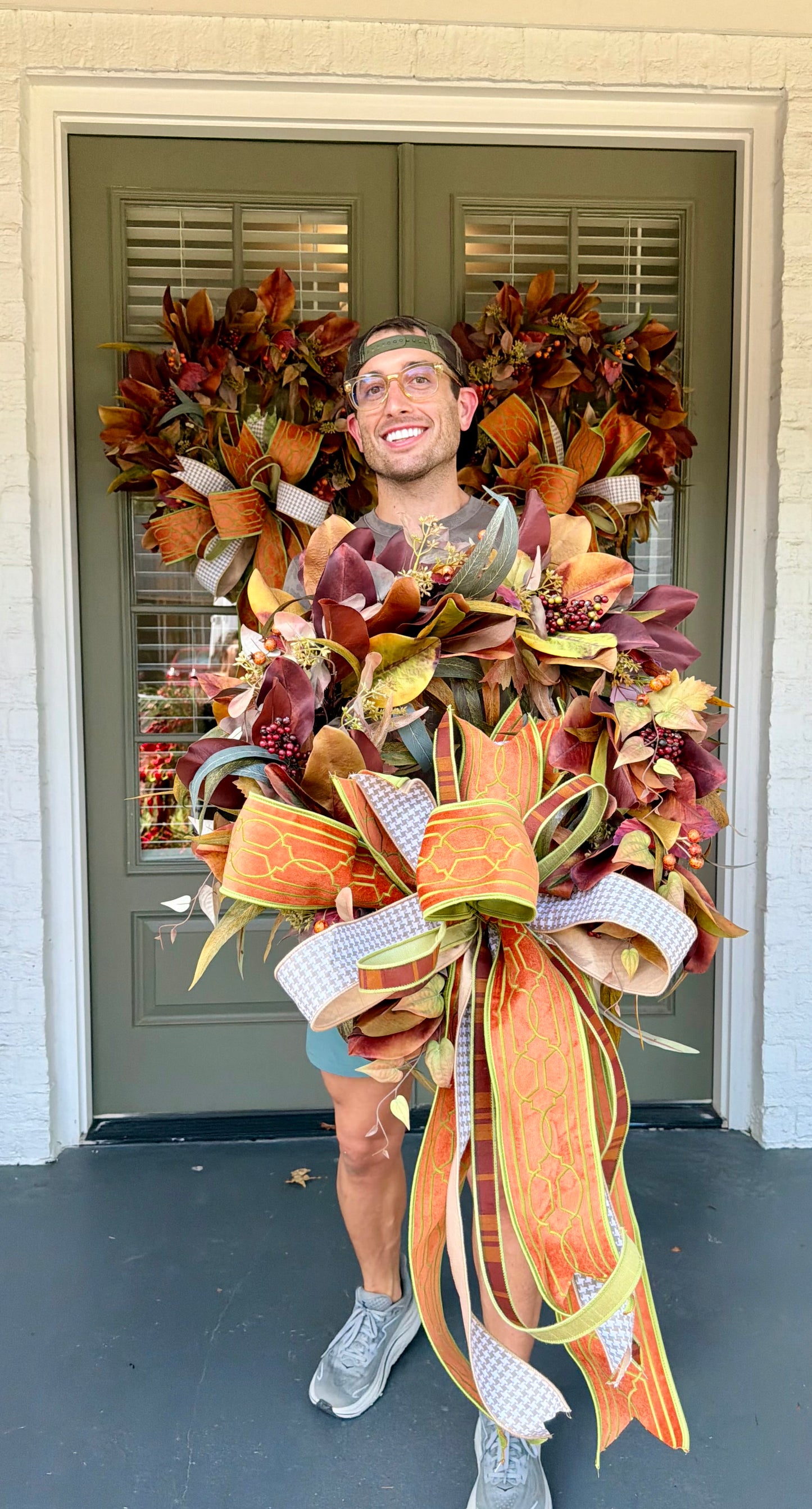 JME fall faux MAGNOLIA WREATH paired with other fall botanicals. About 26inches in diameter. Paired with a JME hand tied bow of orange and browns. Some fluffing may be required upon receiving.