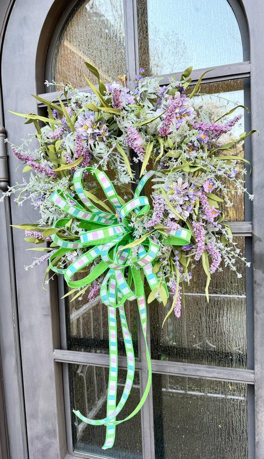 Soft purple Wildflower mixed wreath with a hand tied JME bow. Made from 1 inch striped ribbon. About 24 inches in diameter.