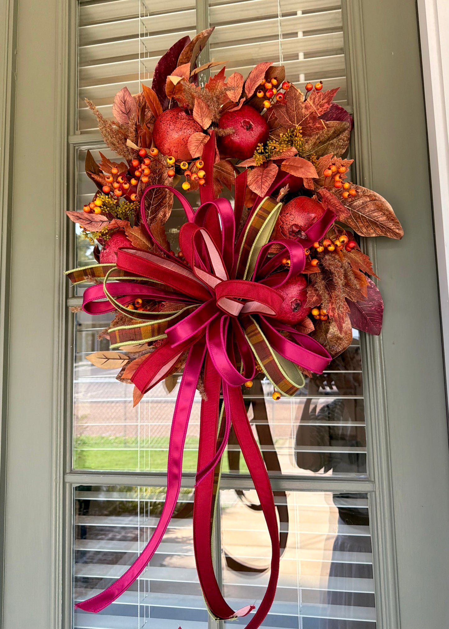 Faux POMEGRANATE fall wreath with a JME hand tied bow of an assortment of 1in ribbons. About 24 inches wide. Some fluffing might be required upon receiving.