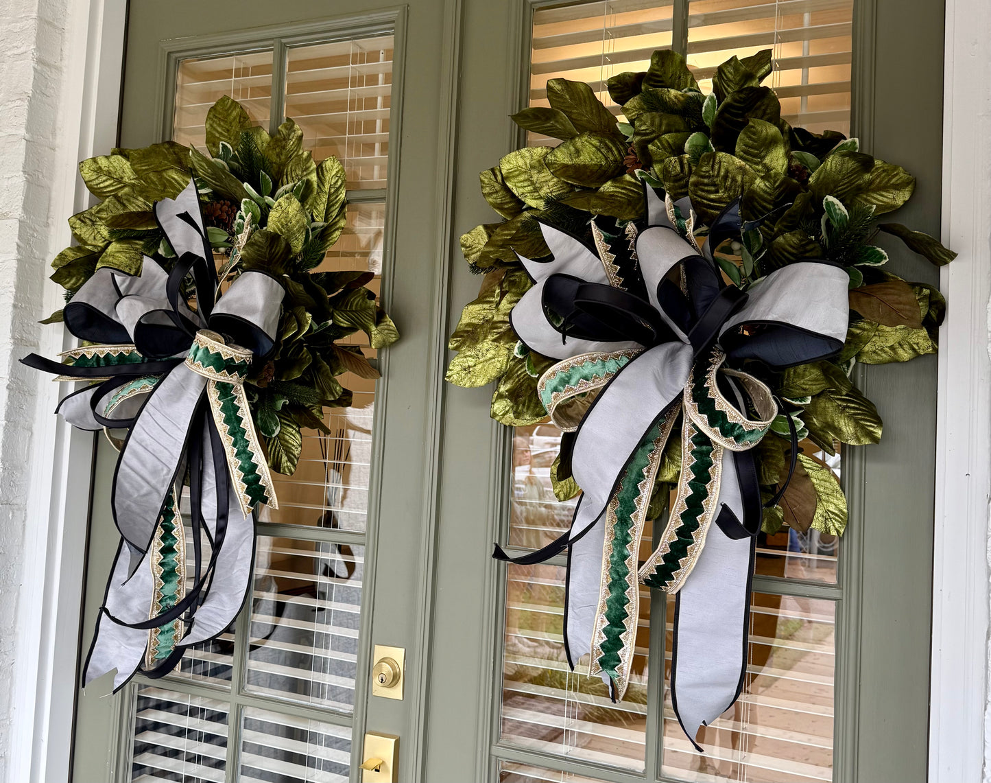 Handmade wreath with metallic green magnolias and a sophisticated JME handtied bow. About 24inches wide.
