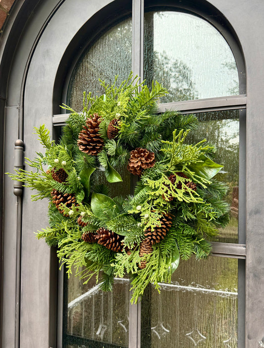 Faux Mixed Foliage Winter Wreath  with juniper berries, and pinecones. Perfect to add to any window door or space throw a bow on it and you are good to go! 24 inches wide.