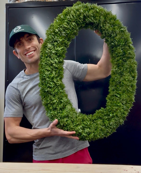 Oval frosted faux cedar wreath. 23inches wide by 30.5 inches long