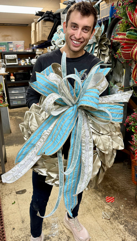 Silver magnolia leaf wreath with sky blue and platinum bow. Perfect for the winter! Approximately 24 inches wide.