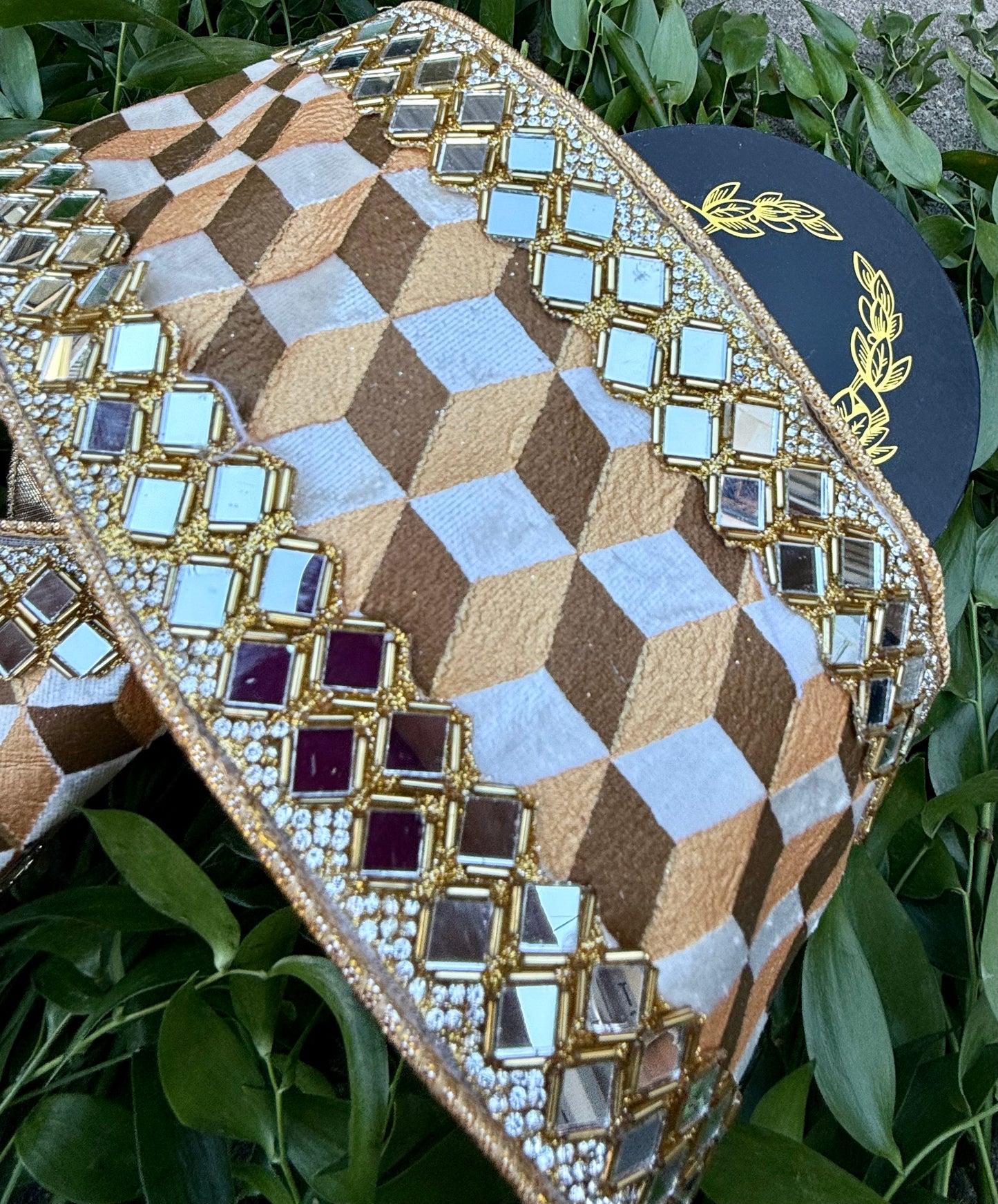 JME Heavy wired ribbon. Geo brown/gold/white pattern ribbon with mirrored diamond trim work. Back with gold metallic. 4“ x 5 yards.