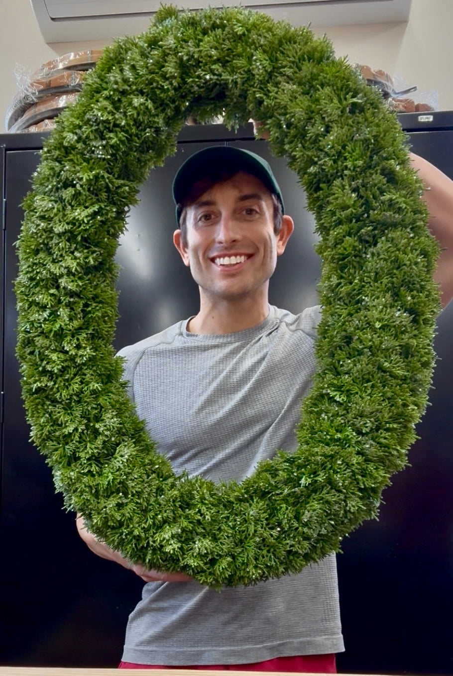 Oval frosted faux cedar wreath. 23inches wide by 30.5 inches long