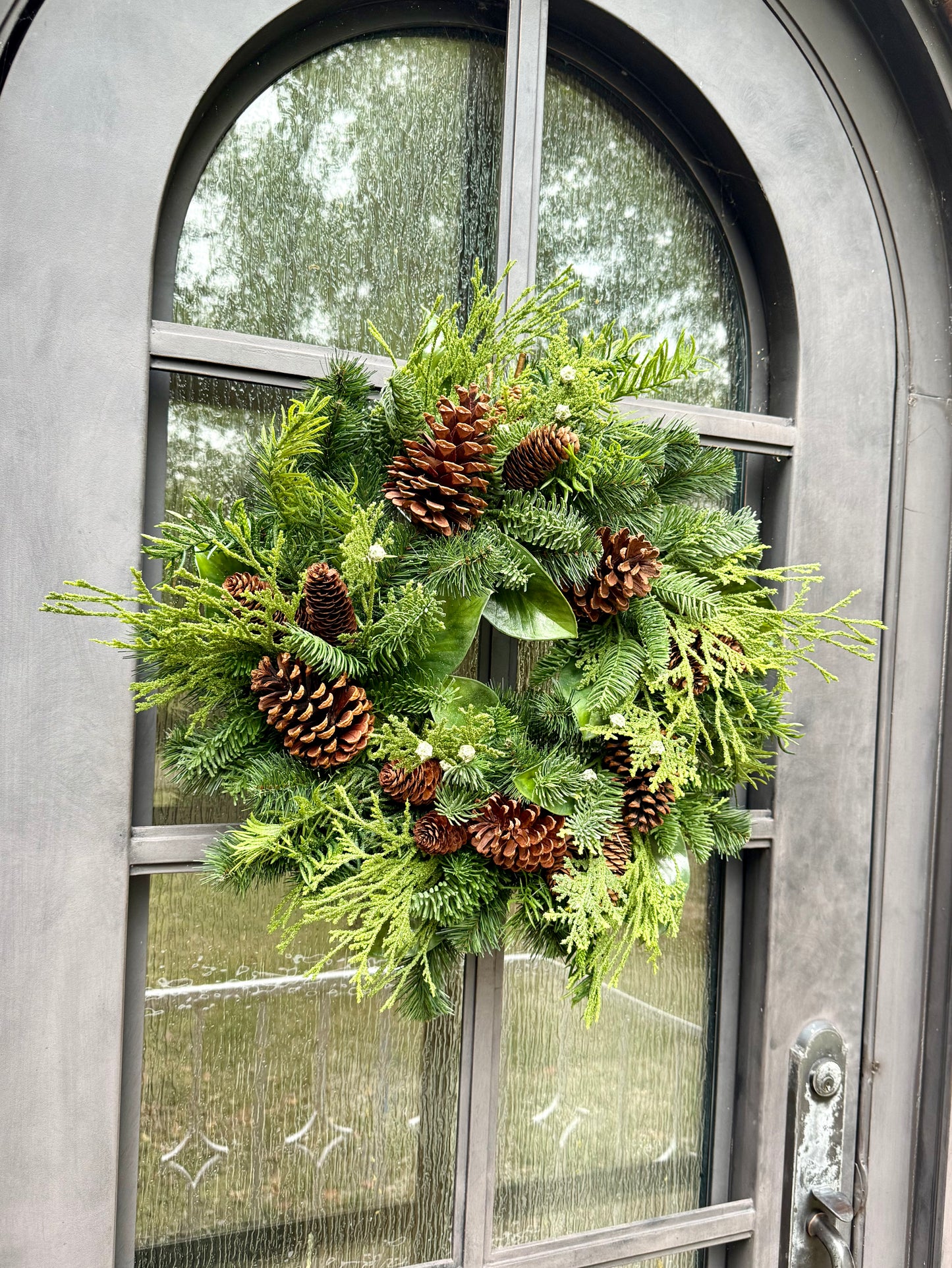 Faux Mixed Foliage Winter Wreath  with juniper berries, and pinecones. Perfect to add to any window door or space throw a bow on it and you are good to go! 24 inches wide.
