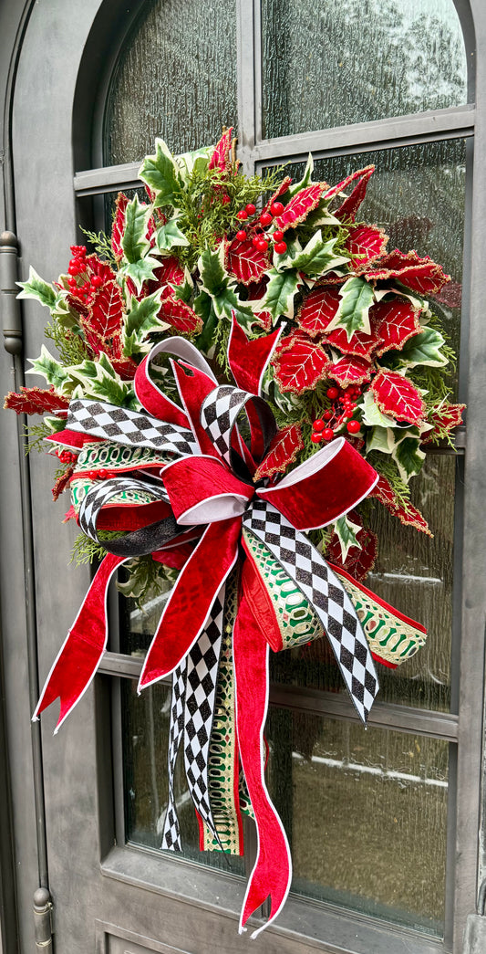 Glitzy Christmas wreath. Hand made by JME , adorned with velvet red holly leaves and paired with a JME bow. Mirrored ribbon and red velvet. What more could you asked for? About 24 inches wide