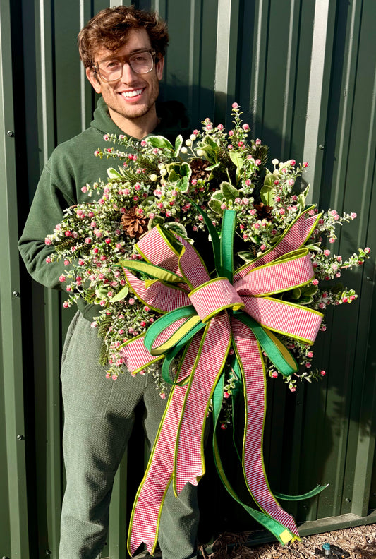 Faux Red snow berry and mixed foliage wreath. Handmade by JME paired with a JME handtied bow. About 24 inches wide.