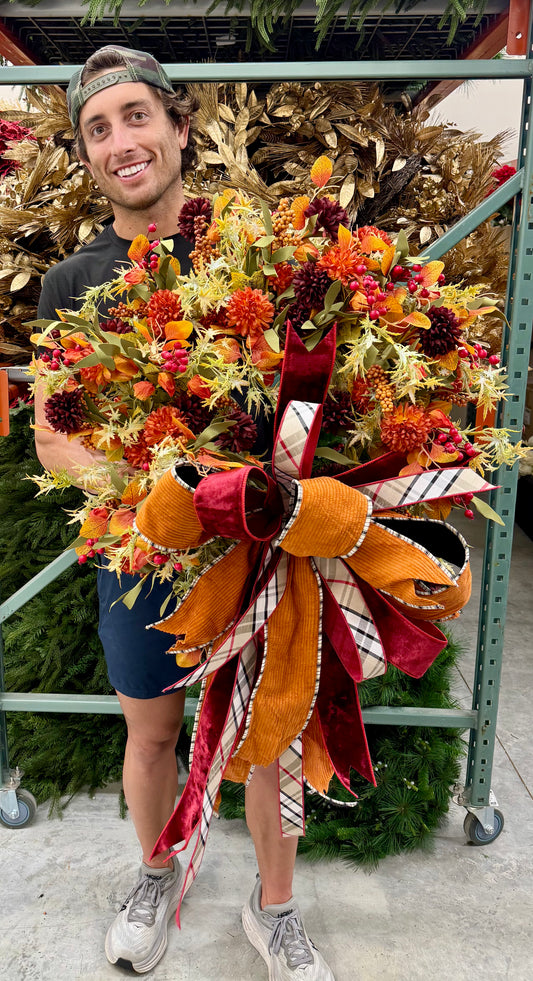 Faux Mixed fall foliage with mum flowers in Chinese lanterns with a JME bow. About 24inches wide.
