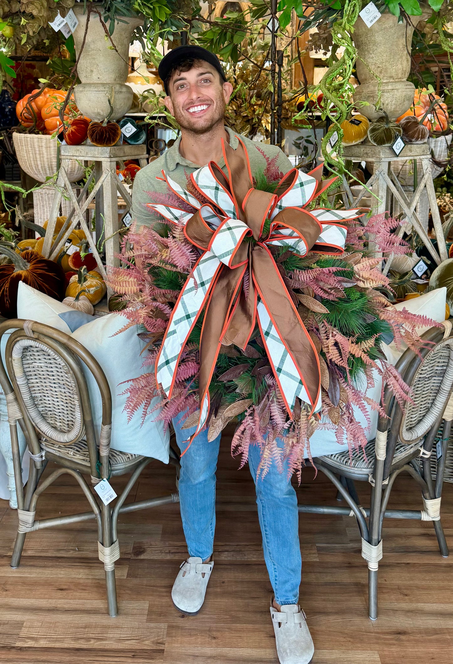 JME MADE faux fall wreath with ferns, bay leaves, and pine. With a JME tied bow. About 24 inches wide.
