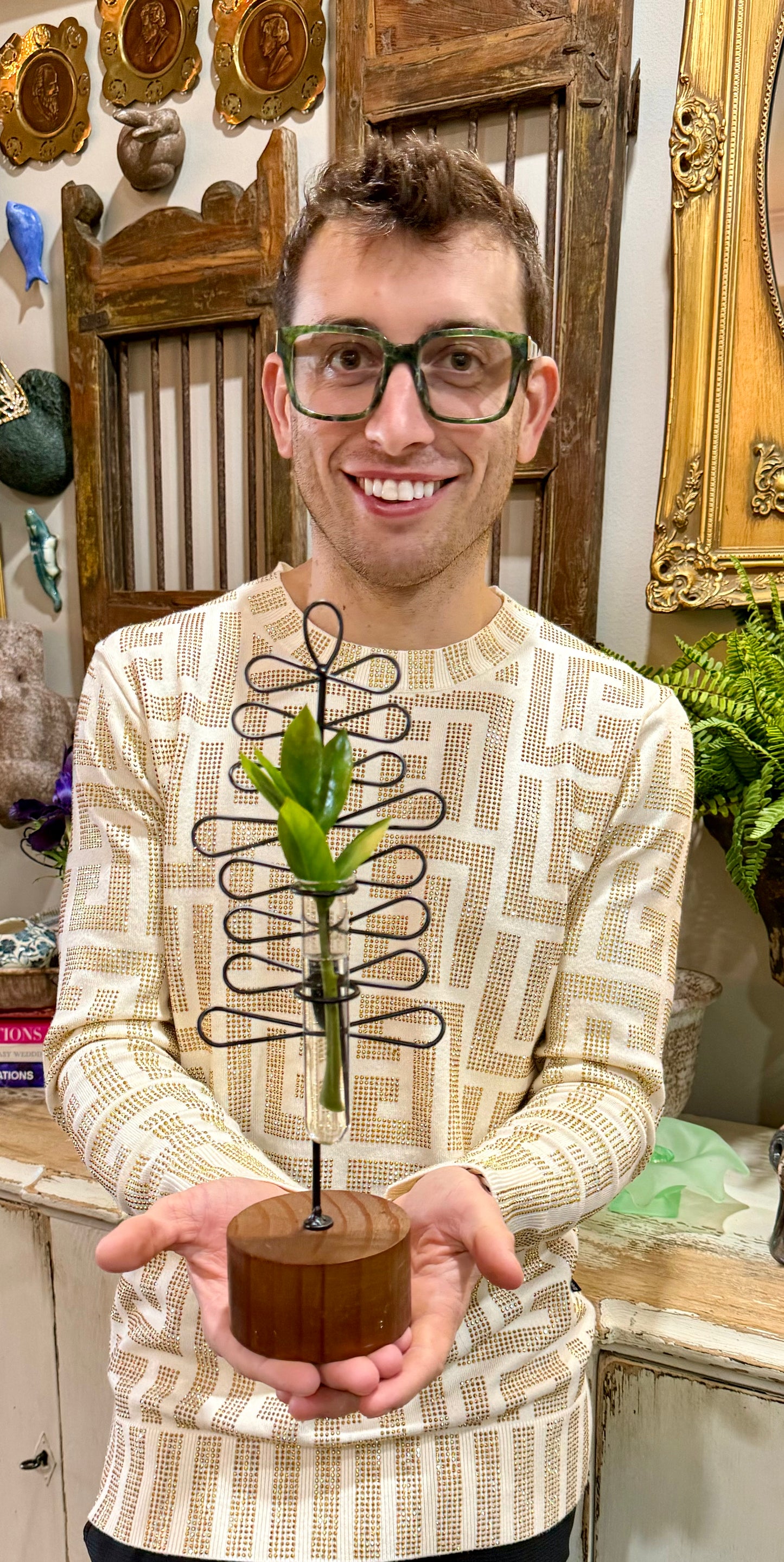 Metal leaf bud vase on a wooden base.