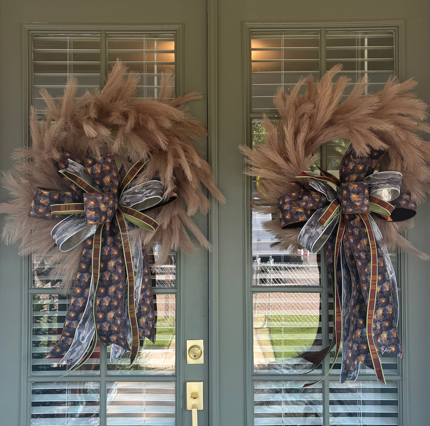Faux Taupe Plume Wreath paired with a JME hand tied bow featuring a brown and silver fall colored ribbon combo. Approximately 26 inches in diameter. Some fluffing may be required upon arrival.