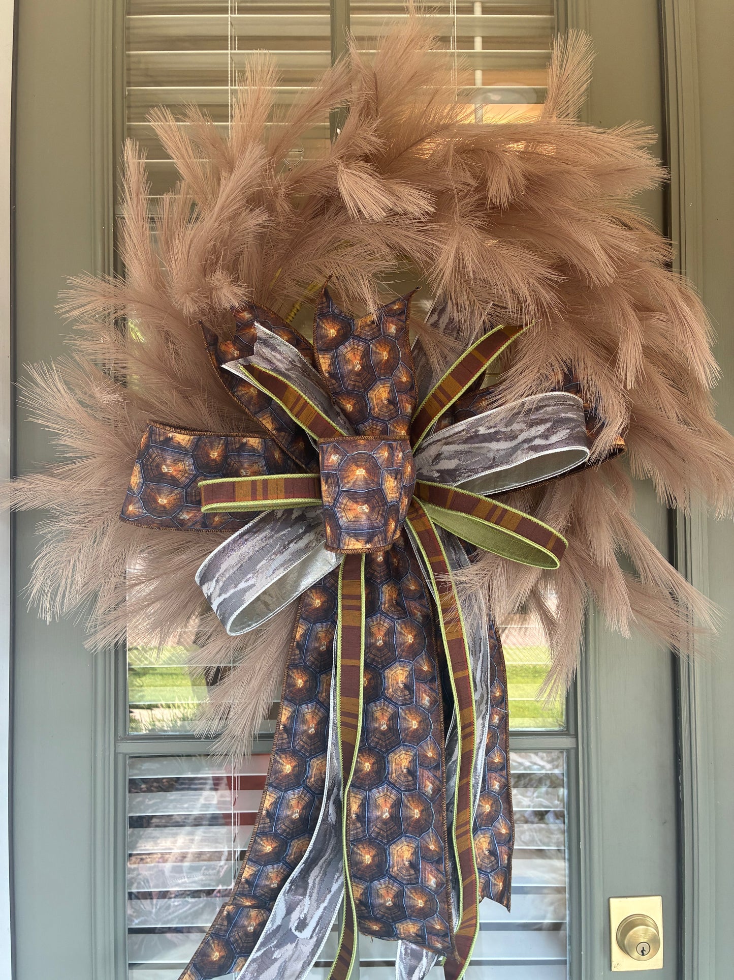 Faux Taupe Plume Wreath paired with a JME hand tied bow featuring a brown and silver fall colored ribbon combo. Approximately 26 inches in diameter. Some fluffing may be required upon arrival.
