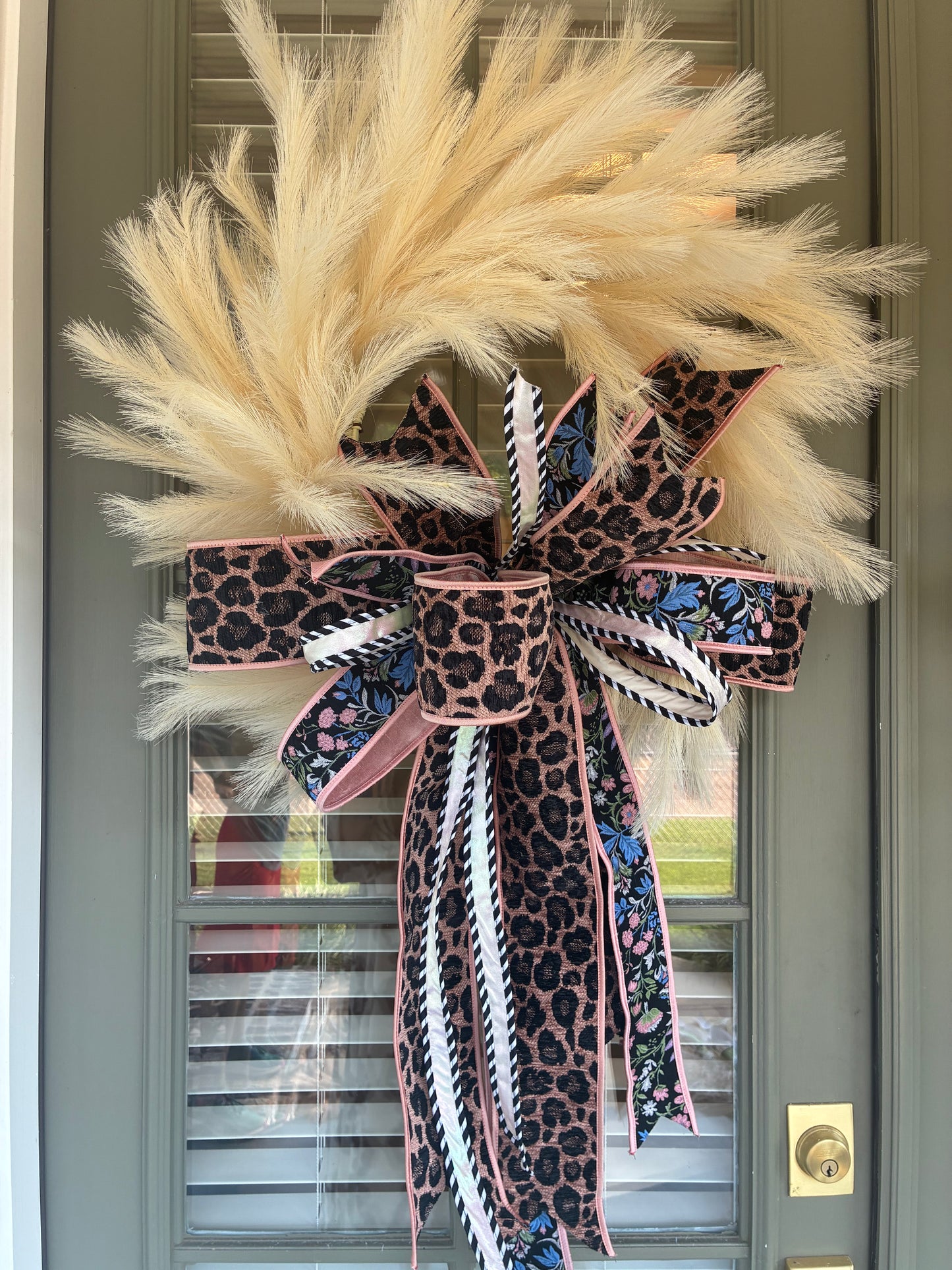 Faux Cream Plume Wreath paired with a JME hand tied bow featuring a pink and black Leopard Chenille and floral ribbon combo. Approximately 26 inches in diameter. Some fluffing may be required upon arrival.