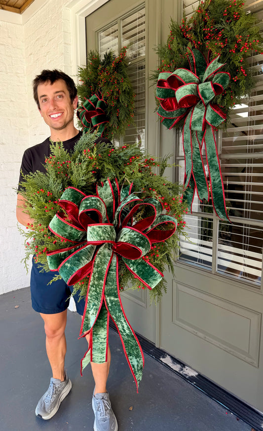 Green Velvet bow JME handmade wreath made with mixed winter foliage and red berries and a JME green velvet bow backed in metallic red. Approximately 24inches in diameter.