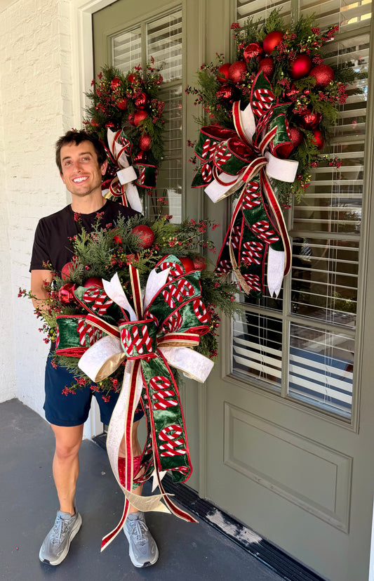 HO HO HO handmade JME wreath of mixed green foliage, red berries, and red ornaments. Paired with  hand tied JME bow.